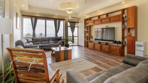 Un salon spacieux doté d’un grand téléviseur à écran plat, d’étagères en bois et d’un coin salon confortable.