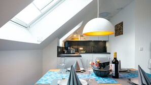 A dining area with a skylight, modern pendant light, and a view of the kitchen.