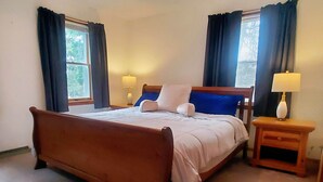 A bedroom with a wooden bed, two bedside tables with lamps, and a window with curtains. - The Fox Den Comfy Lower Unit (Lake Elmo)