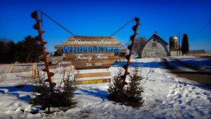 A wooden sign with the text "Whippletree Family Farm" and "Est. 1869" in front of a barn. - The Fox Den Comfy Lower Unit (Lake Elmo)