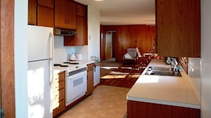A kitchen with wooden cabinets, a white refrigerator, a stove, and a sink. - The Fox Den Comfy Lower Unit (Lake Elmo)