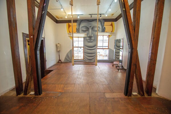 A spacious room with wooden flooring, a large window, and a mural of a face on the wall.