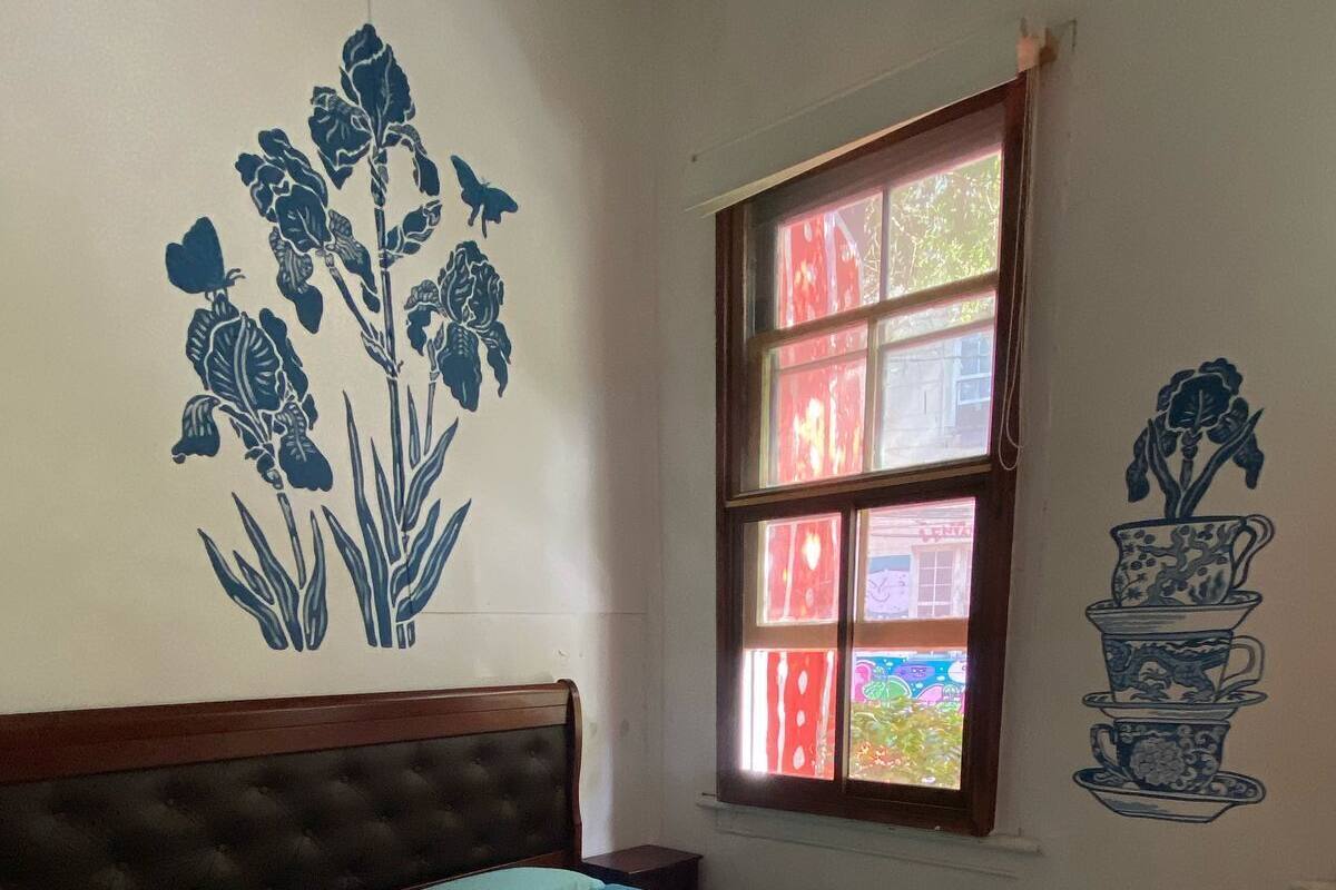A bedroom with a bed, a window, and wall art.