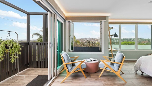 A modern room with large windows, a balcony, and a view of the city. - 2 bedroom tropical beach escape (Bondi Beach)