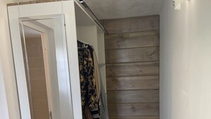 A narrow hallway with a wooden wall, a patterned floor, and a partially open door leading to a bathroom. - AU Jardin D'eden (Le Gosier)