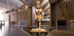 A large statue in a spacious, modern lobby with a high ceiling and patterned walls. - King tout pyramid  (Giza)