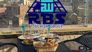 Ett bord med mat och dryck, utsikt över pyramiderna och logotypen för RBS Tourism Group.