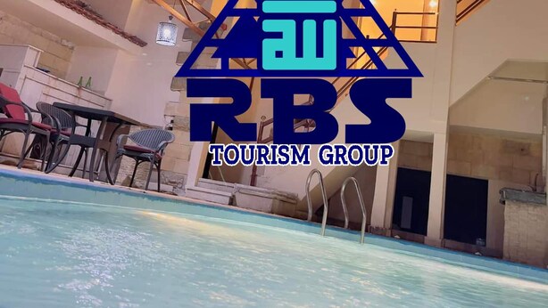 En flervåningsbyggnad med en swimmingpool, utomhusplats och en logotyp för RBS Tourism Group.