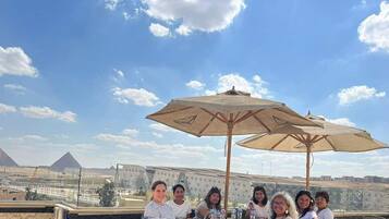 A group of people seated at an outdoor table with a view of pyramids in the background.