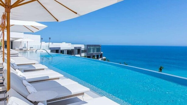 A poolside area with white lounge chairs and umbrellas, overlooking a clear blue ocean. - Garza Blanca Three Bedroom Loft Los Cabos (Cabo San Lucas)