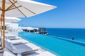 A poolside area with white lounge chairs and umbrellas, overlooking a clear blue ocean. - Garza Blanca Three Bedroom Loft Los Cabos (Cabo San Lucas)