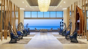 A modern lobby with a view of the ocean, featuring hanging chairs and a central seating area. - Garza Blanca Three Bedroom Loft Los Cabos (Cabo San Lucas)