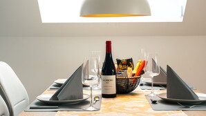 Et spisebord dækket med en vinflaske, glas og en kurv med snacks.