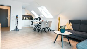 En moderne lejlighed med spiseplads, en sofa og et lille bord med en plante.