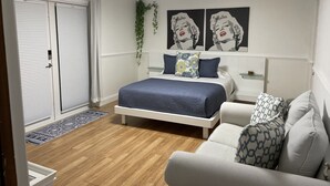 Een slaapkamer met een bed, nachtkastje, stoel, kledingkast en plafondventilator.