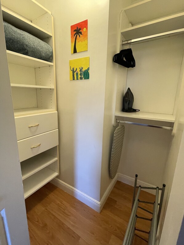 En walk-in-garderob med öppna hyllor, en klädstång och en stege.