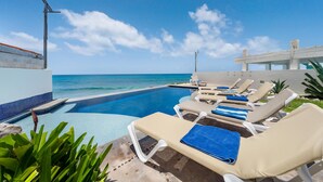 A poolside area with lounge chairs, a clear view of the ocean, and a tiled pool. - 4 BR Oceanfront Villa with Pool (Isla Mujeres)