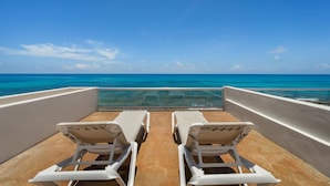 A balcony with two white lounge chairs facing a clear blue sea. - 7 BR Oceanfront Villa w/Private Pool (Isla Mujeres)