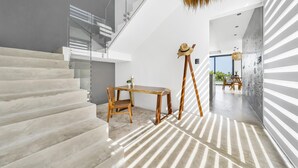 Un intérieur moderne avec un escalier, une table en bois et un chapeau posé sur un présentoir.
