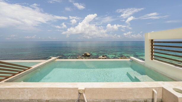 Une piscine à débordement à l’eau d’un bleu cristallin, offrant une vue sur l’océan.