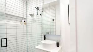 Un baño moderno con cabina de ducha de vidrio, un lavabo blanco y un espejo sobre él.