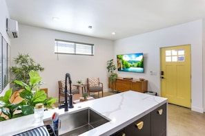 Una cocina moderna con encimera de mármol, un lavamanos y un comedor con sillas y una mesa.