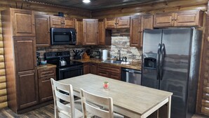 Una cocina con armarios de madera, un refrigerador de acero inoxidable, un microondas, una estufa y un lavabo.