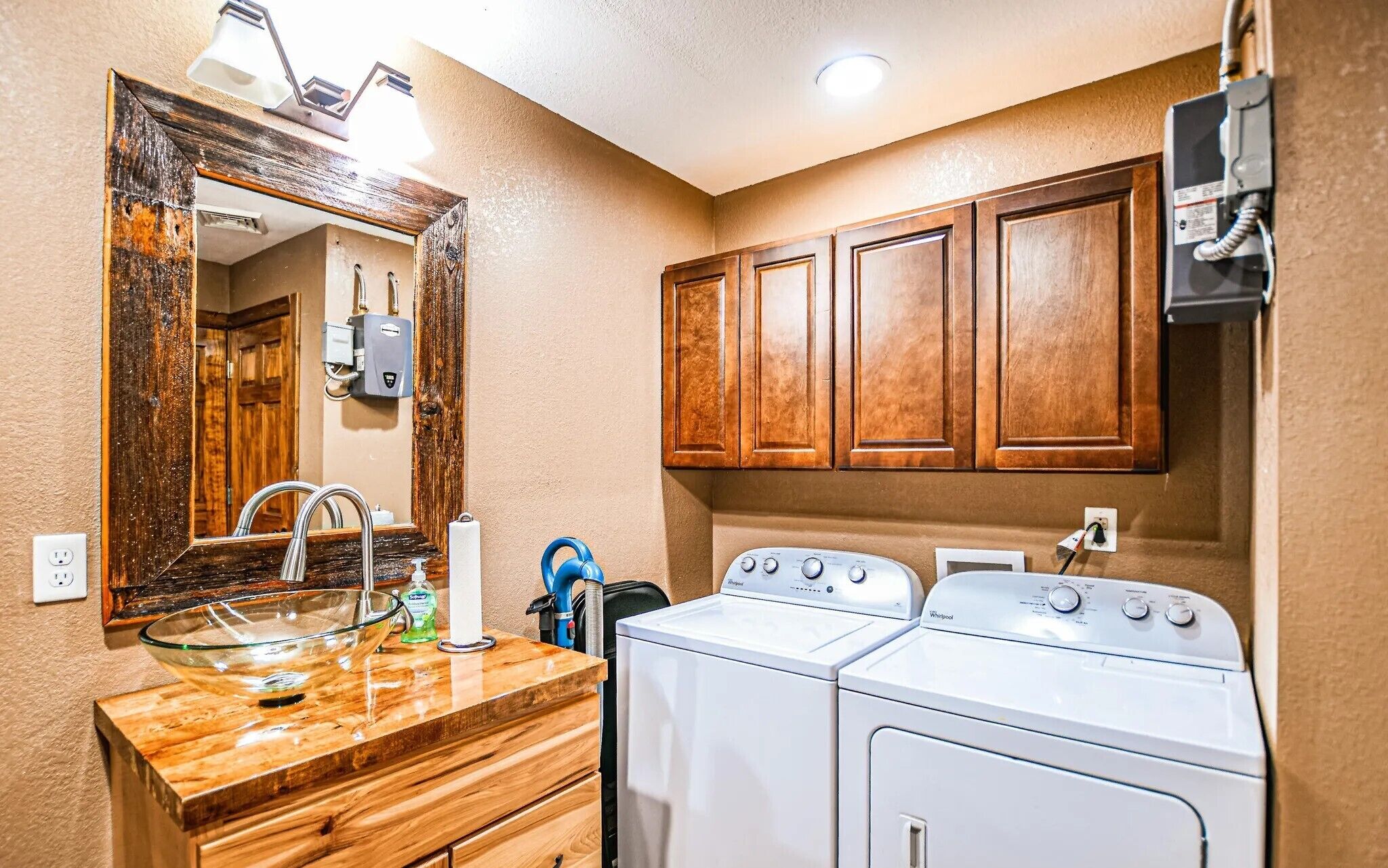 Un baño con un tocador de madera, un lavabo, un espejo y dos lavadoras Whirlpool blancas.