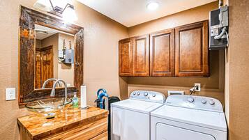 Un baño con un tocador de madera, un lavabo, un espejo y dos lavadoras Whirlpool blancas.