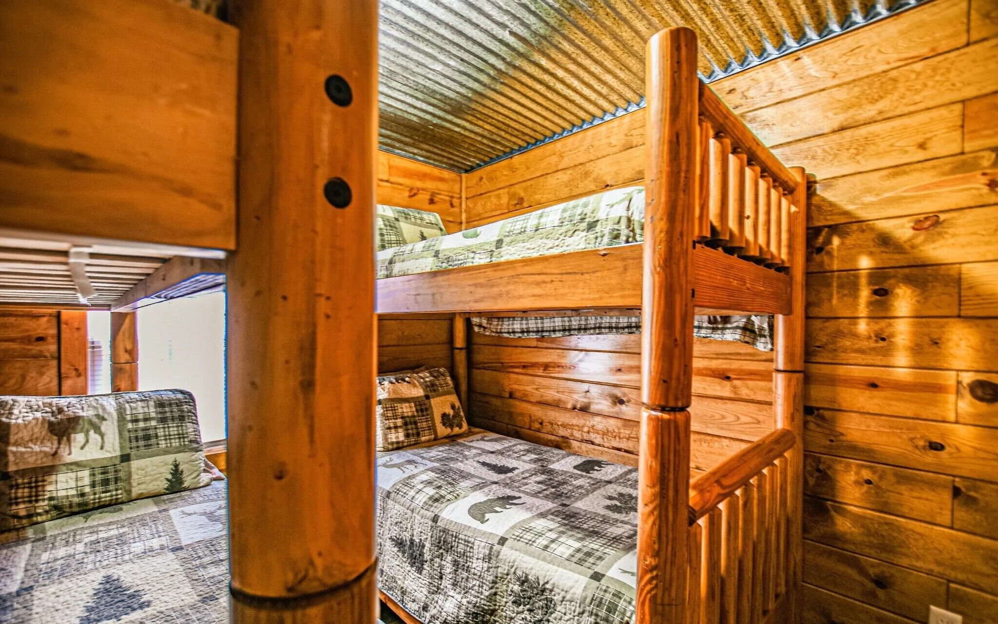 Interior de una cabaña con literas, paredes de madera y techo de metal.
