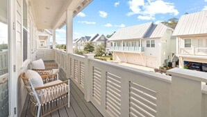 Varanda com mobiliário de vime, vista para casas vizinhas e céu limpo.