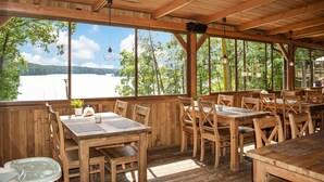 Eine Holzterrasse mit Tischen und Stühlen mit Blick auf einen See.