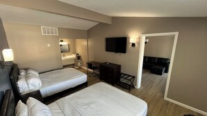 A hotel room with two beds, a desk, a TV, and a bathroom. - Valley Inn and Suites (French Lick)