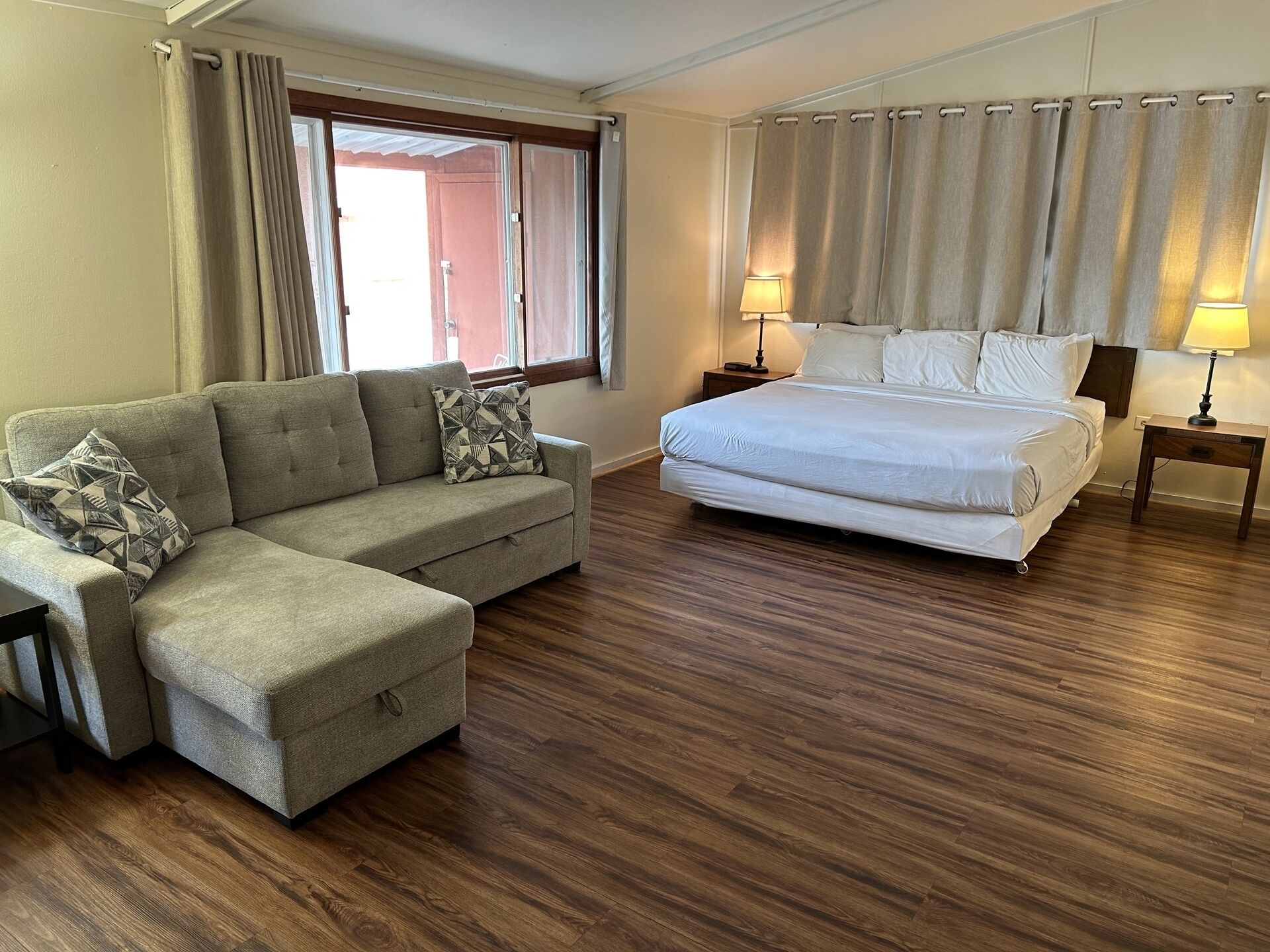 Een slaapkamer met een bed, een sofa en een nachtkastje met lampen.