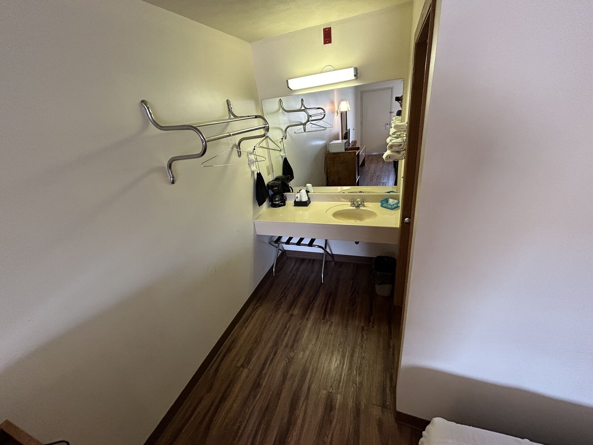 A bathroom with a sink, mirror, towel rack, and a wooden floor.