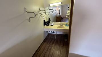A bathroom with a sink, mirror, towel rack, and a wooden floor.