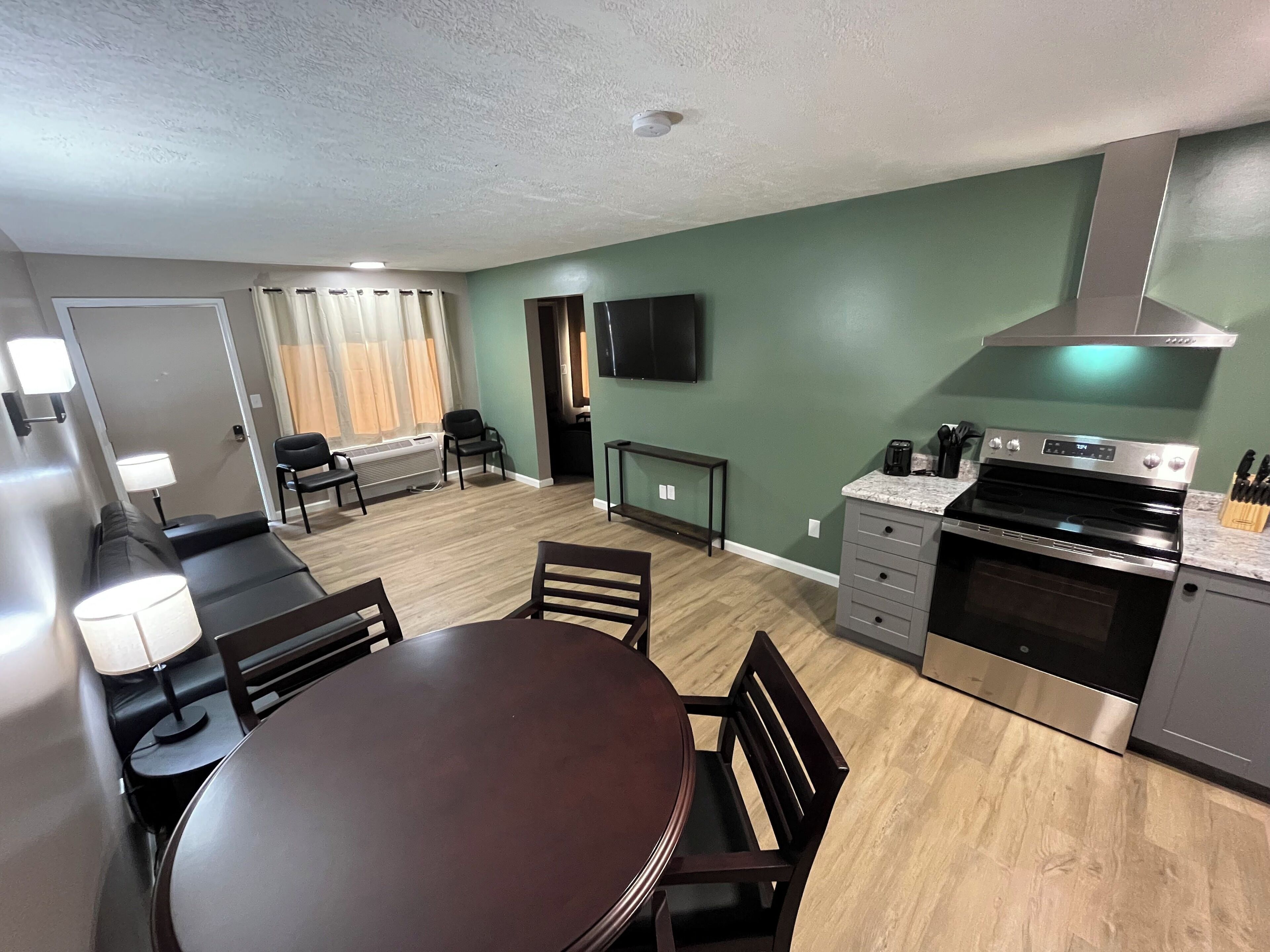 A compact kitchen with a dining area, a built-in oven, and a flat-screen TV.