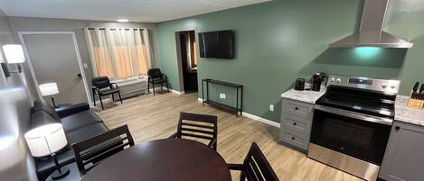 A compact kitchen with a dining area, a built-in oven, and a flat-screen TV.
