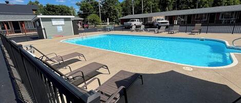 Une piscine avec des chaises longues et un petit bâtiment en arrière-plan.