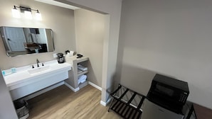 A modern bathroom with a white sink, a mirror, a coffee maker, and a microwave. - Valley Inn and Suites (French Lick)