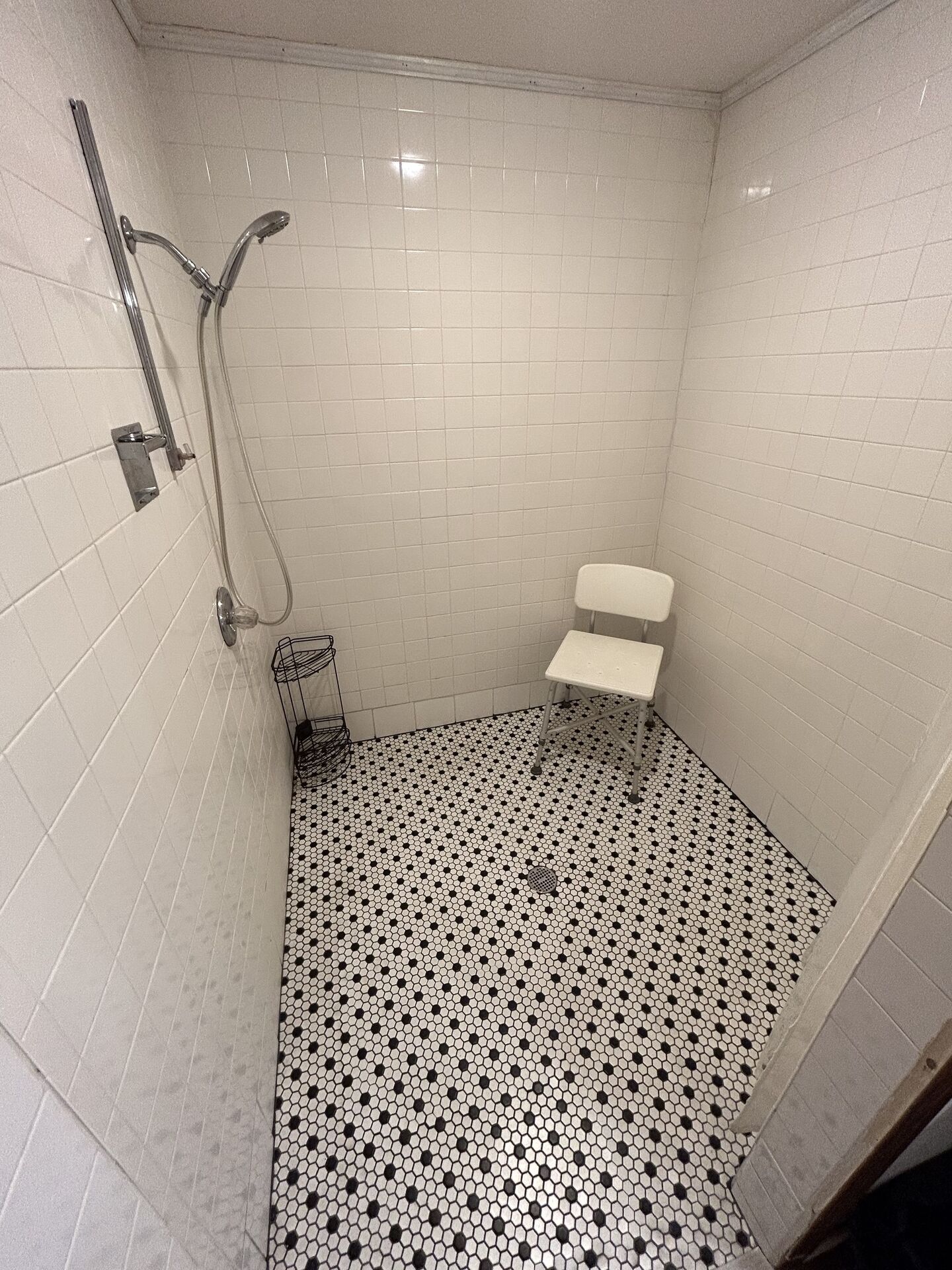 Een kleine betegelde badkamer met toilet, douche en wastafel.
