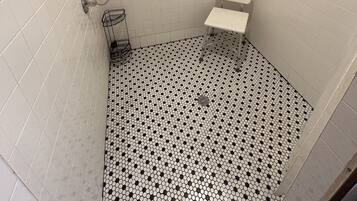 Een kleine betegelde badkamer met toilet, douche en wastafel.
