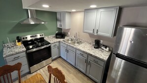 A kitchen with stainless steel appliances, white cabinets, and a granite countertop. - Valley Inn and Suites (French Lick)