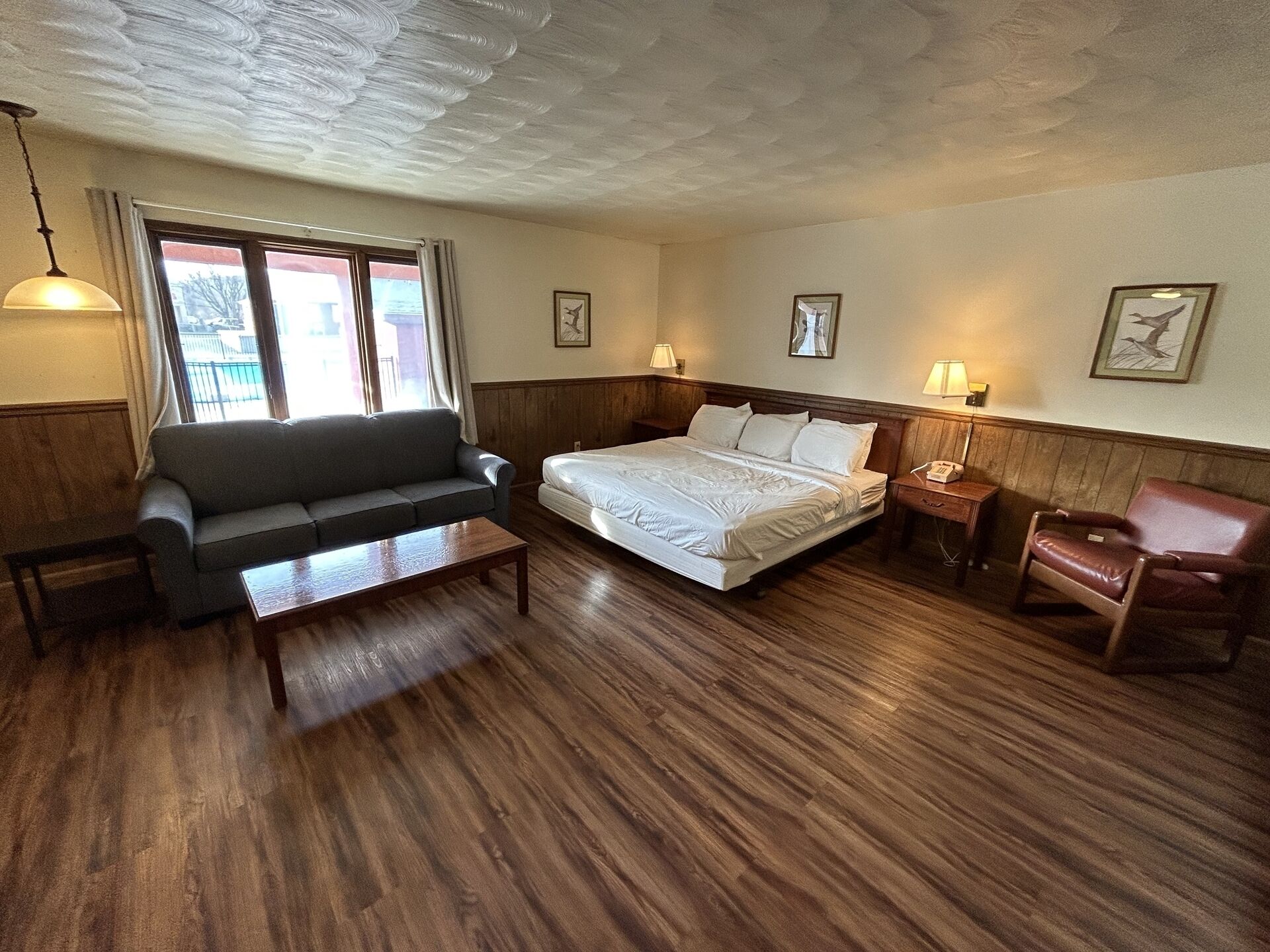 A hotel room with a bed, a sofa, a small table, and a chair.