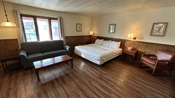 A hotel room with a bed, a sofa, a small table, and a chair.