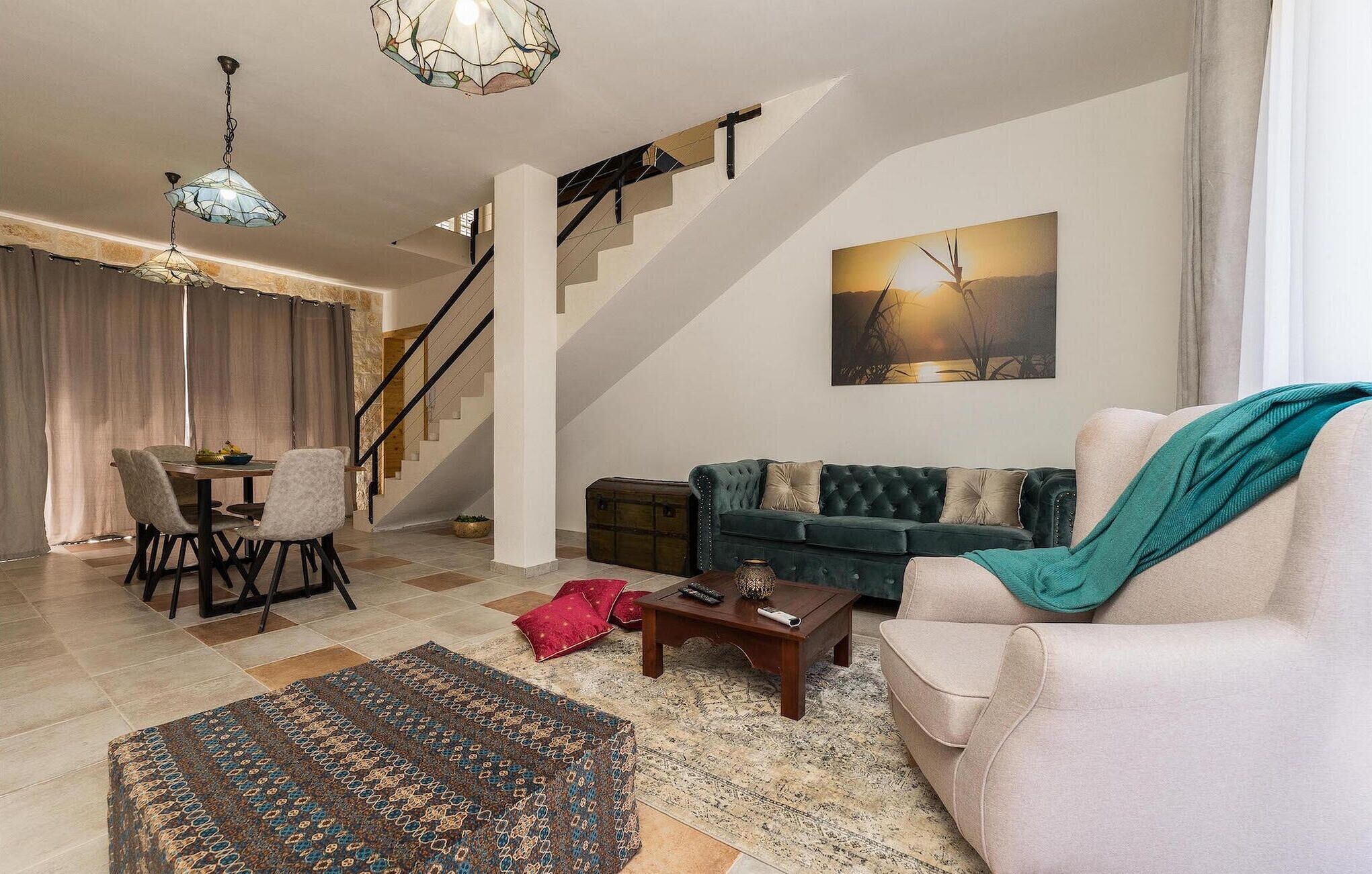 Ein geräumiges Wohnzimmer mit Treppe, einer Couch, einem Couchtisch und einem Essbereich.