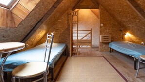 Ein kleines, gemütliches Schlafzimmer im Dachgeschoss mit zwei Betten, einem Tisch und einem Stuhl.