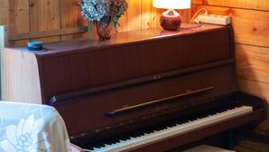 Ein Holzpiano mit einer Bank, eine Vase mit Blumen und eine Lampe auf einer Holzoberfläche.