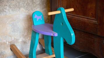 Un caballo balancín de madera con asiento morado y patas turquesa.