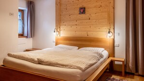 Une chambre à coucher avec une tête de lit en bois, un lit avec une literie blanche, une table de chevet et une fenêtre avec des rideaux.